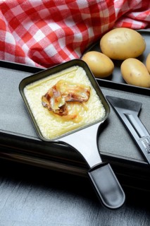 Raclette, melted raclette cheese with bacon in pans and ingredients