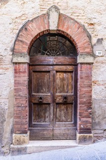 Weathered old round arch front door, Motepulciano