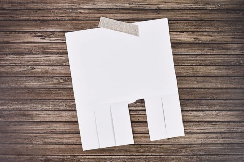 White empty tear-off stub paper note without text on wooden wall,