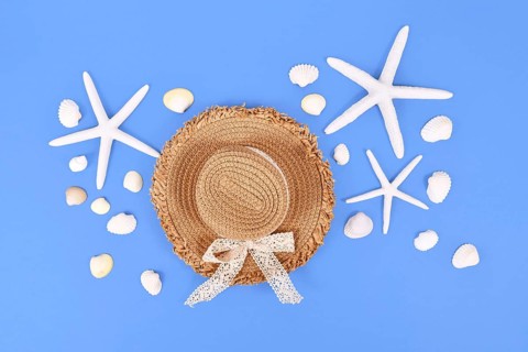 White starfish, seashells and summer straw hat on blue background