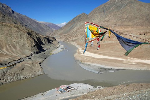 Confluence of the Indus and Zanskar rivers in the Himalayas, prayer flag in front