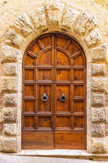 Round arched house entrance door, framed with light-coloured stones