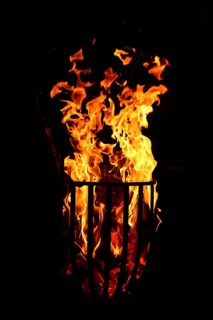Metal fire basket with burning wood at night,
