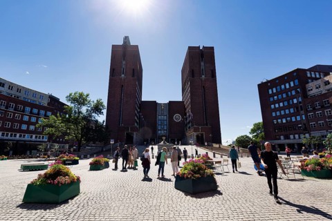 Pedestrians in front of monumental city hall with two towers, north side in summer