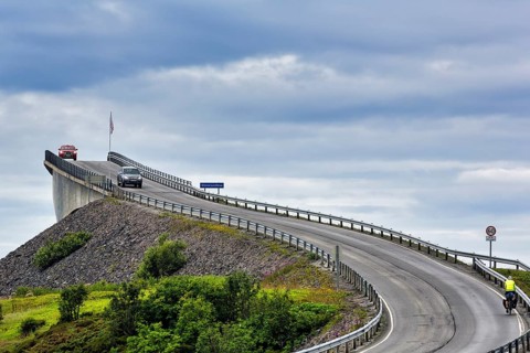 Cyclist and car on Atlantic Road, curvy bridge Storseisundbrua