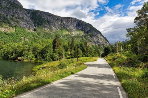 Single-lane country road through valley, river Aura