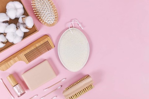 Eco friendly wooden beauty and hygiene products like comb and soap on pink background,