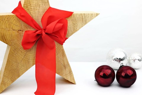 Christmas wooden star with a red bow on a white background, silver and red Christmas tree balls on the side