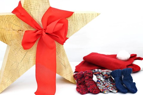 Christmas wooden star with a red bow isolated against a white background, Self-knitted socks on the side