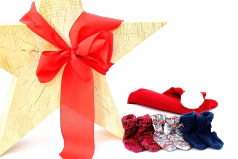 Christmas wooden star with a red bow isolated against a white background, Self-knitted socks on the side