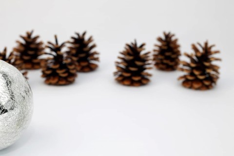 Silver Christmas tree ball and fir cone or pine cone cropped against white background with sharpening gradient,