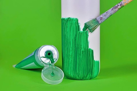 Concept for greenwashing with white plastic bottle being painted green,