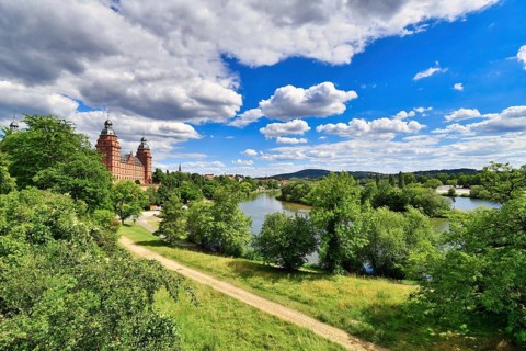 View over beautiful German city Aschaffenburg with Main river, palace called Schloss Johannisburg and green park on sunny summer day