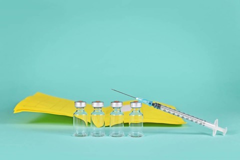 Corona booster vaccine concept with 4 vials with syringes and certificate of vaccination in background with copy space,