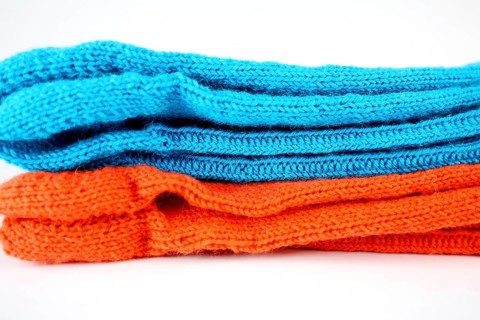Self-knitted socks made of wool isolated against a white background in orange and blue,