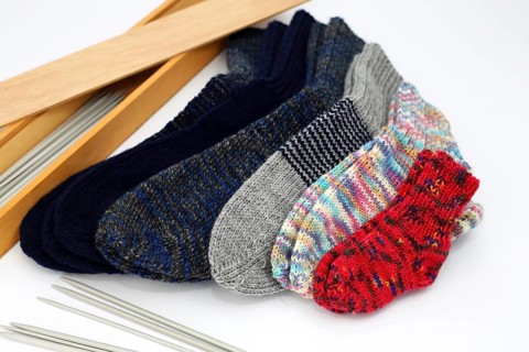 Self-knitted socks made of wool isolated against a white background. In different colours and sizes,