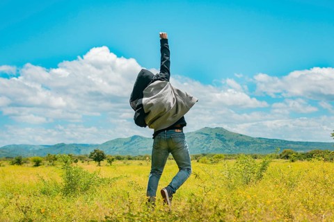 Man from back jumping in a nice field, Rear view of man jumping in the grass raising fist