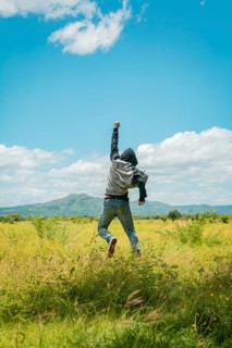 Concept of a free person jumping and raising his arm, Free person jumping with happiness in the field