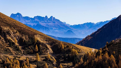 Hiking trail in autumnal mountain landscape, the mountain backdrop of the Dolomites in the background