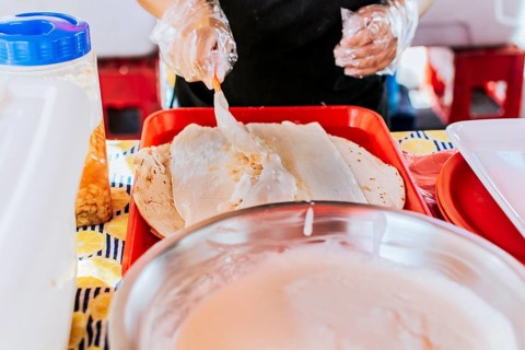Nicaraguan quesillo, traditional Central American food quesillo. Hands making a Nicaraguan quesillo. Close up of hands making a traditional quesillo with pickled onion