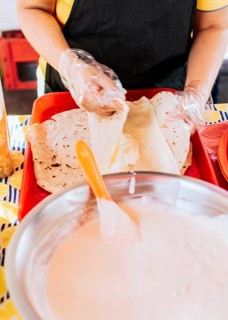 Homemade Nicaraguan Quesillo, traditional Central American food quesillo. Hands making a Nicaraguan quesillo. Close up of hands making a traditional quesillo with pickled onion