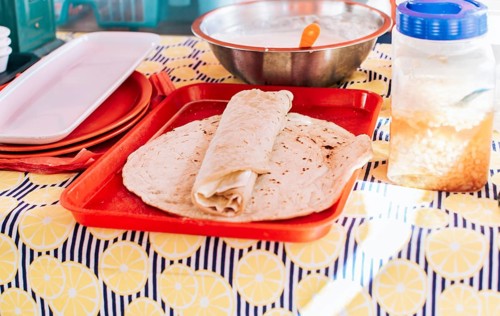 Nicaraguan quesillo made and served on the table. Traditional quesillo with pickled onion and wrapped tortilla. Traditional Nicaraguan Quesillo, food Traditional Large Quesillo served on table