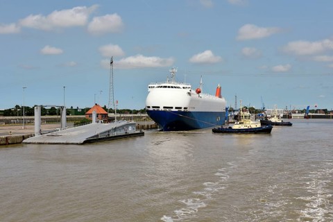 Tugboats move a special ship loaded with cars in the outer harbour, Emden
