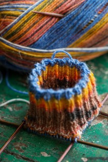 Handwork, knitted sock with knitting needles and wool