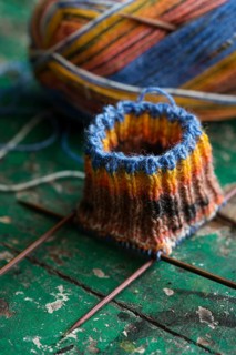 Handwork, knitted sock with knitting needles and wool