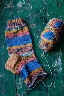 Handwork, knitted sock with knitting needles and wool