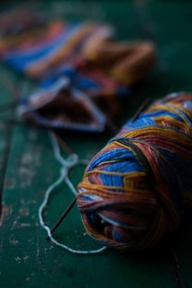 Handwork, knitted sock with knitting needles and wool