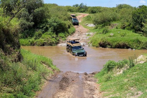 Safari jeep driving through river, Masai Mara National Reserve