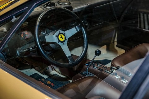 View into interior of Ferrari 512 BB from 70s 1977 with steering wheel with logo jumping horse Cavallino Rampante and lever of manual gear shift, fair Techno Classica