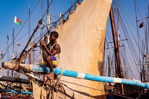 Man sitting on the yard of a fishing boat in the Arab quarter, yard sail behind