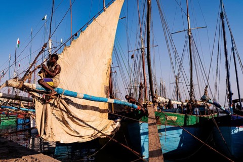 Man sitting on the yard of a fishing boat in the Arab quarter, yard sail behind