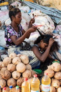 Two woman braiding hair, market stall