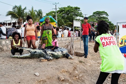 Photographer, photographs family with artificial crocodile