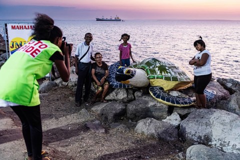 Photographer, photographs family with artificial turtle
