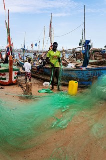 Fishermen mending nets, fishing boats