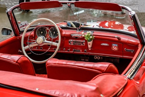 View into interior of convertible classic car Mercedes SL 190 with red leather, white spoke steering wheel