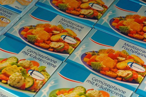 Frozen food, packages with vegetable pan with herb cream in the freezer in a supermarket