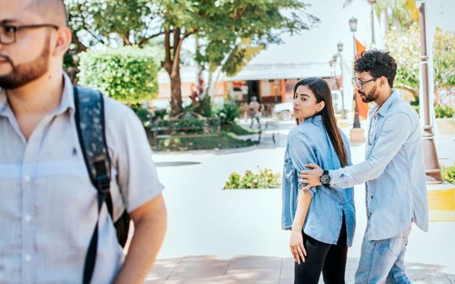 Unfaithful girl looking at another man on street while her boyfriend claims her. Disloyal girlfriend looking at another guy on the street. Unfaithful girlfriend looking at another man on the street
