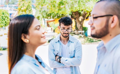 Sad man seeing his girlfriend cheating with his friend outdoors