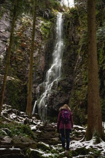 Woman in front of waterfall in winter landscape