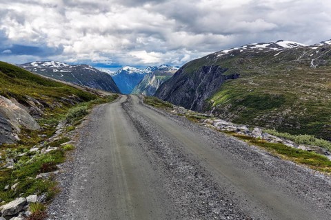 Gravel road through barren mountain landscape with remnants of snow
