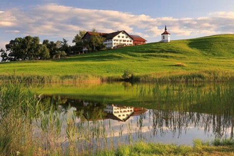 Lake chapel and farmhouse reflected in the lake