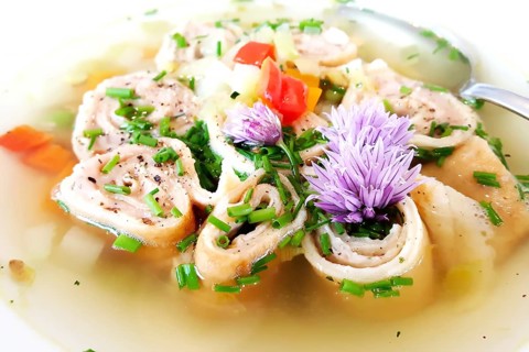 Delicious Braet Strudel soup served in a plate and garnished with chives and chive blossoms