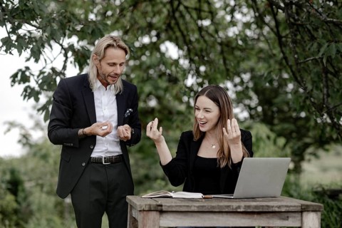 Businessman and businesswoman working in the open on a laptop at a wooden table