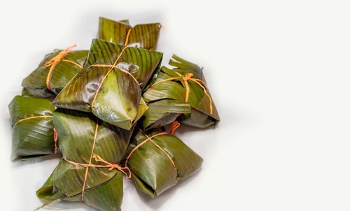 View of homemade Nicaraguan nacatamales with banana leaf on white background