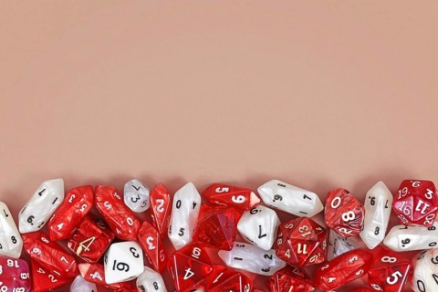 Different red roleplaying RPG dice at bottom of beige background with blank copy space